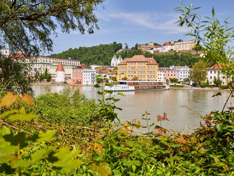 View of an old town by the riverbank with colorful buildings and a boat on the water.
