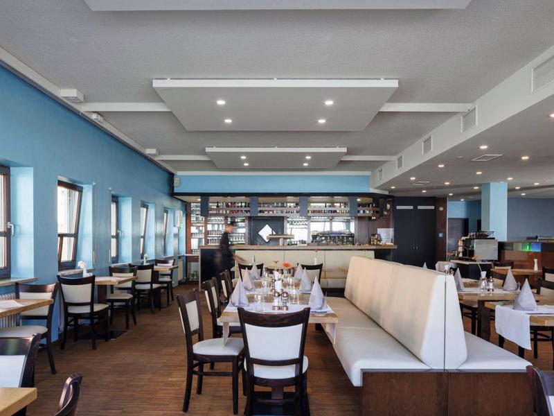 Modern hotel restaurant with blue walls and elegantly set tables.