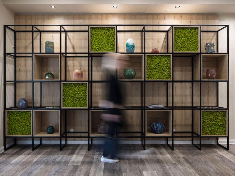 Modern room with large shelf and green decorated compartments on wooden floor.