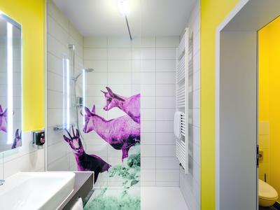 Modernes Badezimmer mit weißen Fliesen, Waschbecken, Spiegeln und lila Wandkunst.