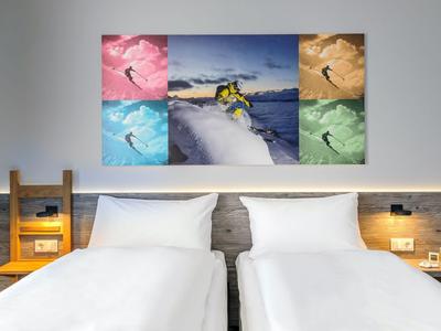 Zwei Einzelbetten in einem Hotelzimmer mit moderner Wandkunst und Leselampen