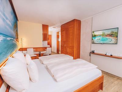 Lichte hotelkamer met twee eenpersoonsbedden, houten meubels en een zeeafbeelding aan de muur.