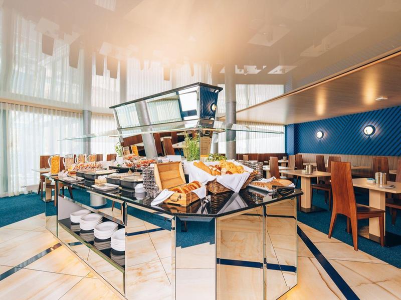 Buffet luminoso con dolci e aree salotto moderne in un ristorante alberghiero.