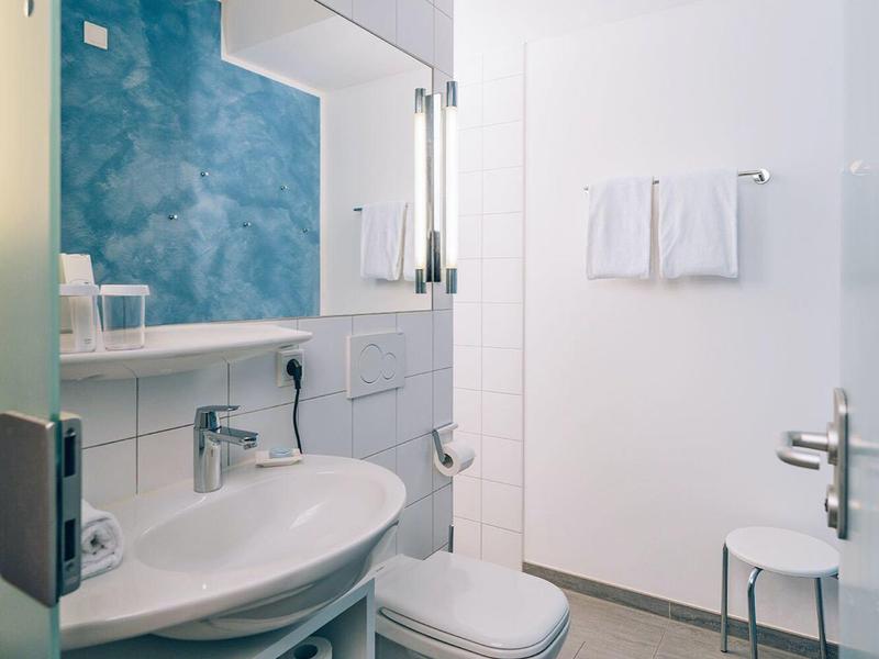 Bagno moderno con lavabo, gabinetto e parete piastrellata blu.