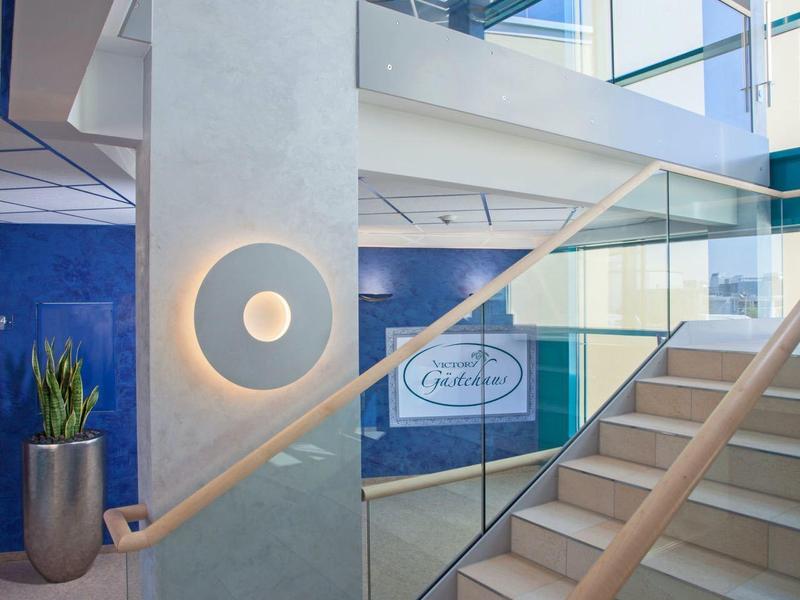 Moderna scala con ringhiera in vetro, corrimano in legno e lampada da parete rotonda in interno luminoso.