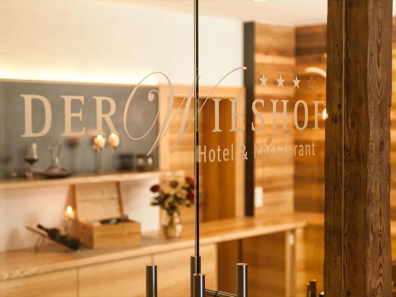 Vue à travers une porte vitrée d'un hall d'hôtel chaleureux avec des détails en bois.