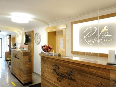 Dobře osvětlený vstup s dřevěnou recepcí a dekorativními cedulemi v hotelu.