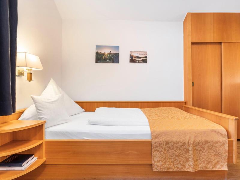 Una camera d'hotel accogliente con letto matrimoniale, mobili in legno e toni caldi.