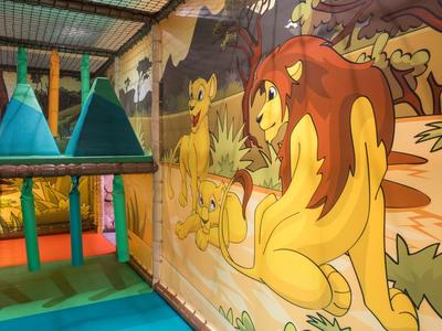 Espace de jeu coloré pour enfants avec pont suspendu et fresque de lions à l'hôtel.