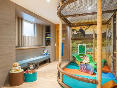 Salle de jeux pour enfants avec structure d'escalade, sièges et jouets colorés dans un espace lumineux.