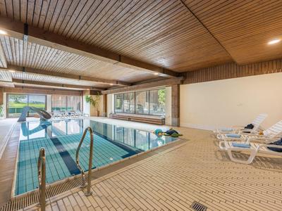Espace intérieur d'hôtel avec piscine chauffée et chaises longues à côté