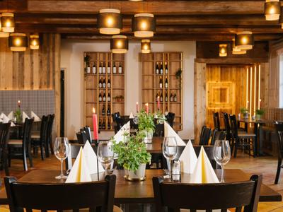 Ein gemütliches Restaurant mit Holzmobiliar, gedeckten Tischen und warmem Licht.