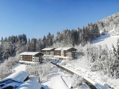 Mehrere Chalets in verschneiter Berglandschaft unter klarem Himmel.