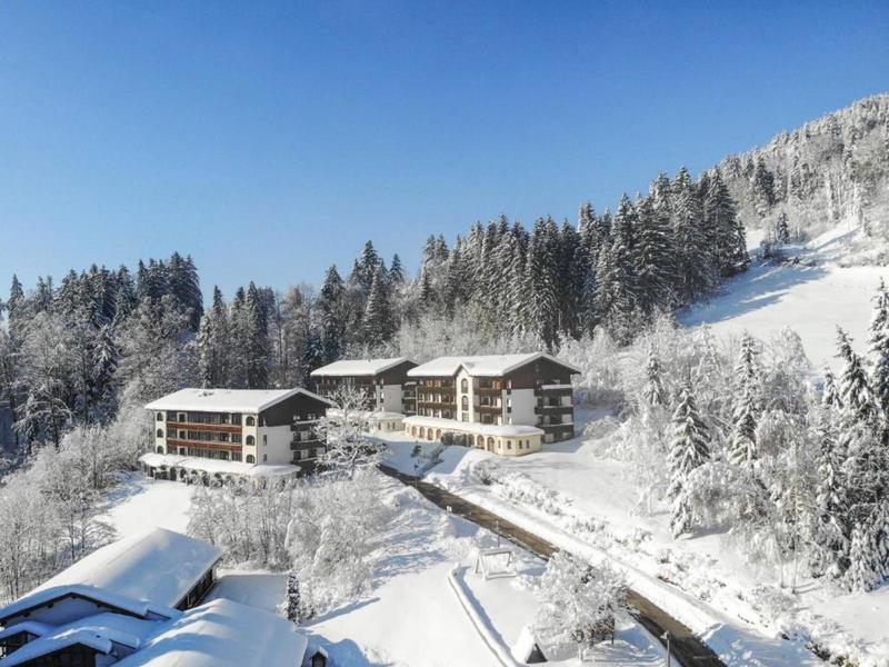 Mehrere Chalets in verschneiter Berglandschaft unter klarem Himmel.