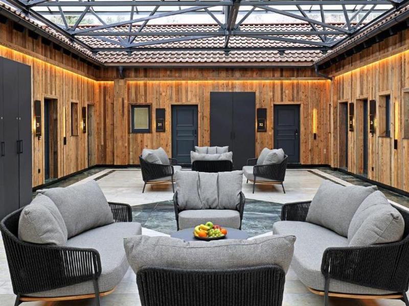 Moderner Sitzbereich mit Sofas und Stühlen in einem Innenhof mit verglastem Dach.