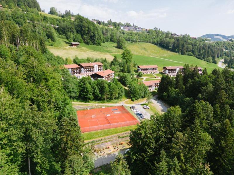 Grünes Tal mit Tennisplatz und mehreren Gebäuden in hügeliger Landschaft.