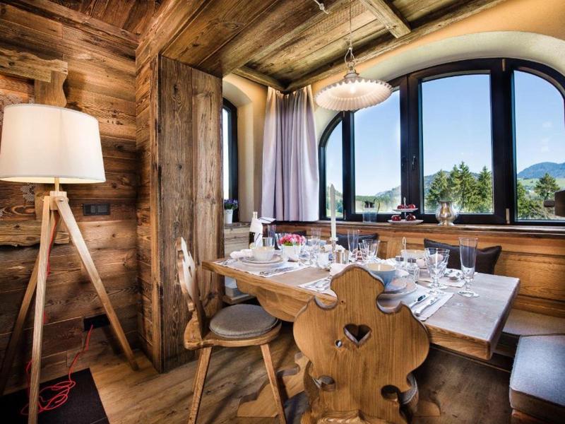 Rustikaler Essbereich mit Holzmöbeln, großem Fenster und Bergblick.