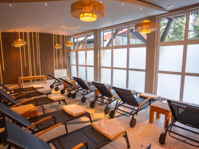 Entspannungsraum mit Liegestühlen und großen Fenstern in einem Wellnessbereich.
