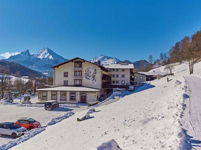 Hotel in besneeuwd berglandschap met heldere blauwe lucht en parkeergelegenheid