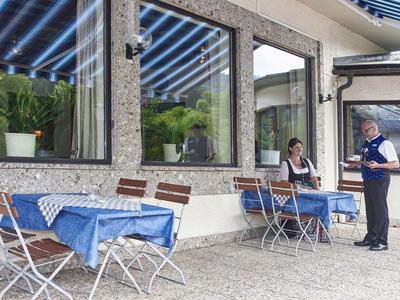 Buitenterras van een café met blauw geruite tafelkleden en gasten.