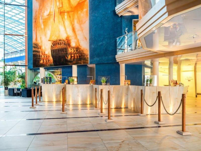 Luxusní hotelová hala s mramorovou podlahou, zábranami a velkým uměleckým dílem na zdi