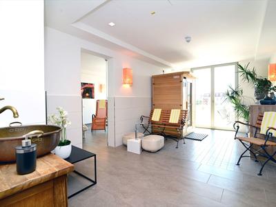 Heller, moderner Warteraum mit Stühlen, Pflanzen und einem Waschbecken auf Holzkommode.