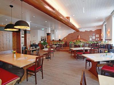 Gemütlicher Speiseraum mit Holzmöbeln, warmen Farben und moderner Beleuchtung.