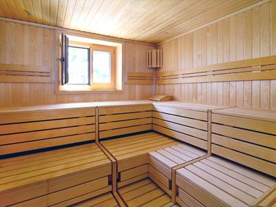 Helles Holzsauna mit mehrstufigen Sitzbänken und offenem Fenster für Belüftung.