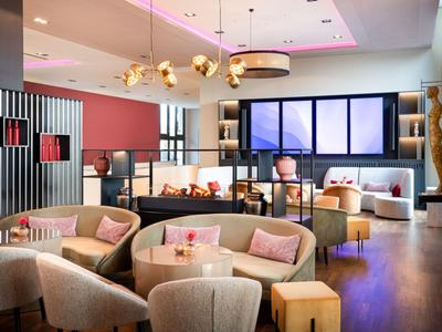 Espace lounge d'hôtel moderne avec fauteuils confortables et éclairage chaleureux.