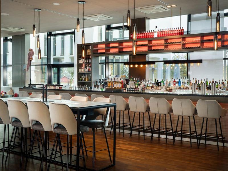 Moderne hotelbar met hoge krukken, lange tafels en grote ramen.