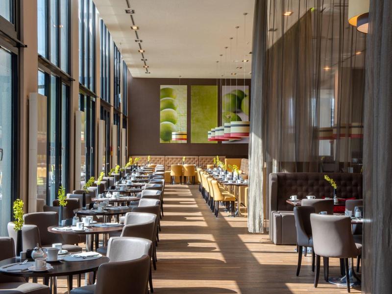 Helder modern restaurant met grote ramen en gedekte tafels in een hotel.