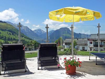 Due lettini su una terrazza con vista sulle montagne e un ombrellone giallo.