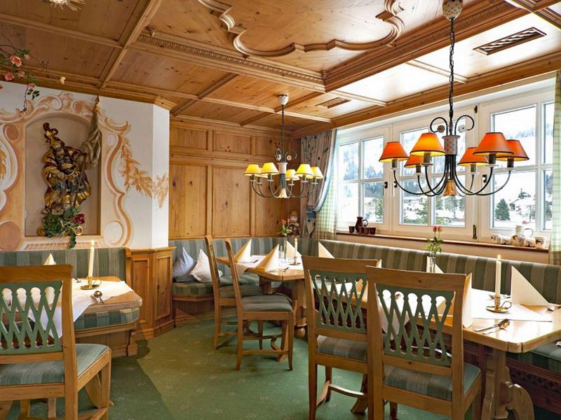 Salle à manger confortable avec mobilier en bois et grandes fenêtres dans un hôtel.