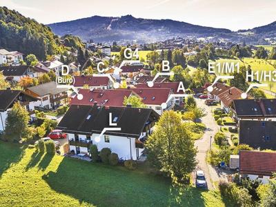 Ländliches Dorf mit Häusern und Hügeln im Hintergrund bei Sonnenschein.