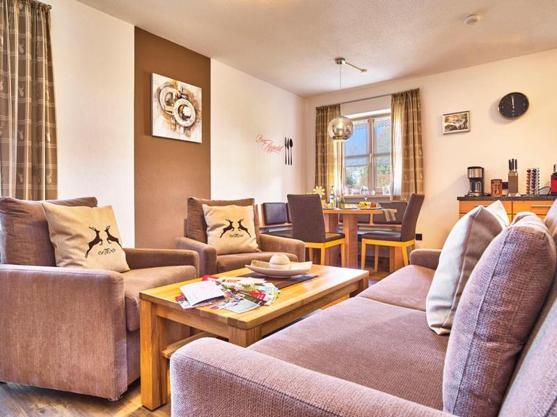 Gemütliches Wohnzimmer mit braunen Sofas, Holztisch und dekorativer Wand im Hotelzimmer.