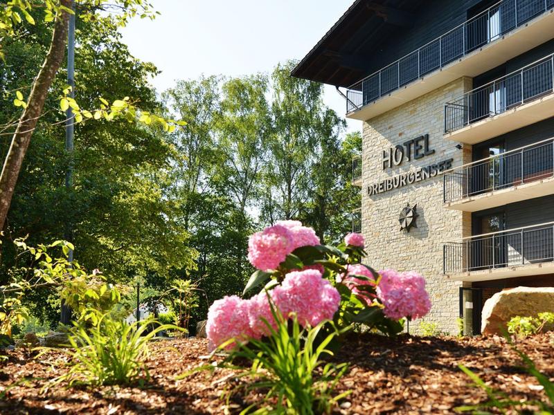 Kwitnące różowe kwiaty obok nowoczesnego budynku hotelu w świetle słonecznym.