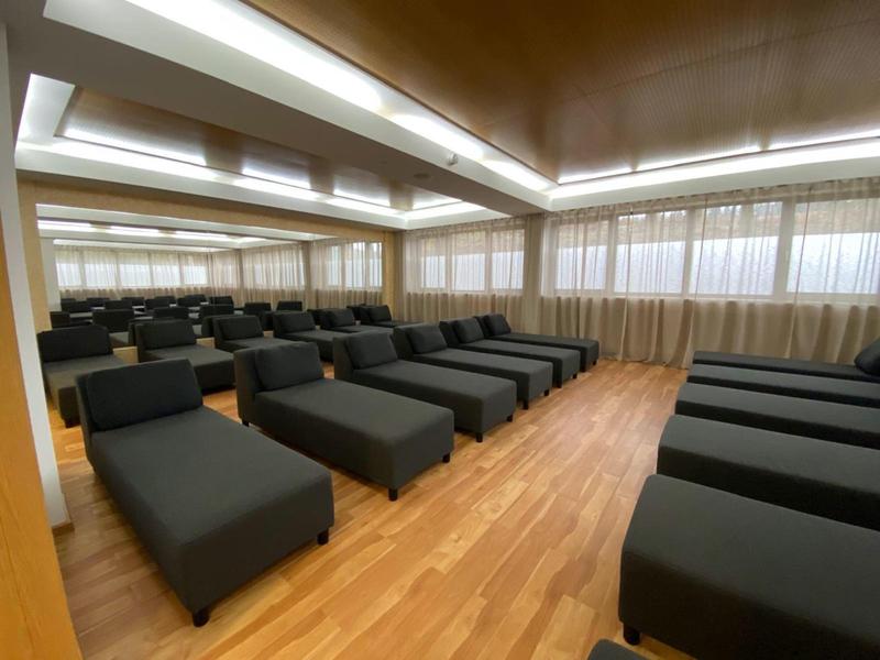 Duży pokój z czarnymi leżakami i drewnianą podłogą, idealny do relaksu w hotelu.