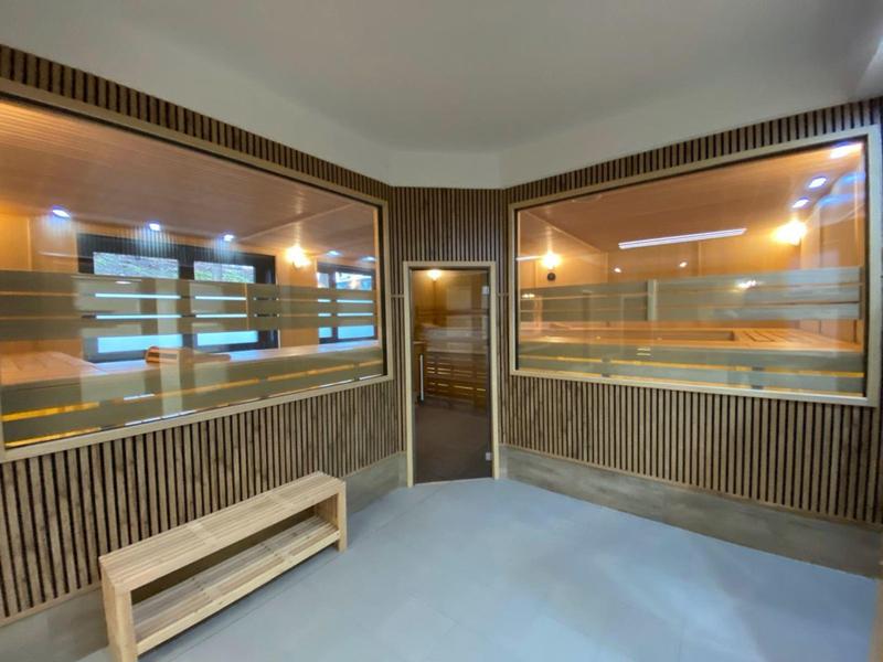 Wnętrze sauny z drewnianymi ławkami i dużymi szklanymi oknami.