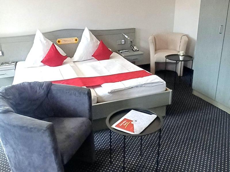 Przytulny pokój hotelowy z łóżkiem podwójnym, fotelem i małym stolikiem.