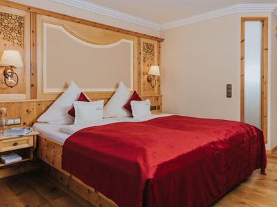 Chambre d'hôtel confortable avec lit double, couvertures rouges et mobilier en bois.