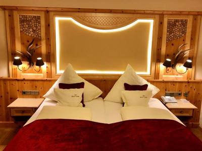 Lit double confortable avec accents rouges et éclairage chaud dans une chambre en bois.