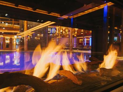 Brasero moderne avec flammes vacillantes devant la piscine éclairée d'un hôtel la nuit