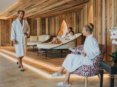 Trois personnes en peignoirs se détendent dans une salle de spa confortable avec panneaux en bois.