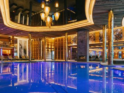 Innenpool in einem luxuriösen Hotel mit warmem Licht und Spiegeldecken.