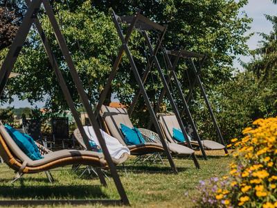Chaises longues extérieures avec coussins sur l'herbe verte par temps ensoleillé.
