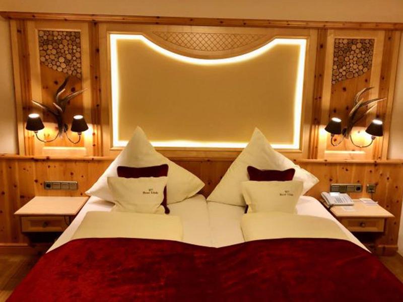 Gemütliches Hotelzimmer mit Doppelbett, Holzwand und dekorativer Beleuchtung.