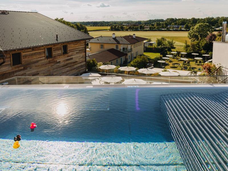Modernes Außenpool mit Liegestühlen und Sonnenschirmen bei Hotel in ländlicher Umgebung