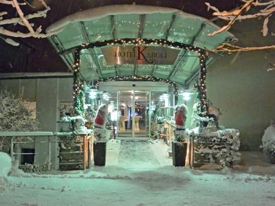 Eingang eines Gebäudes im Winter mit Schnee und Lichterketten beleuchtet.