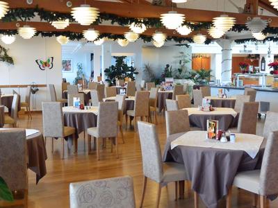 Helles Restaurant mit mehreren runden Tischen und grauen Stühlen auf Holzboden