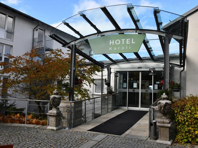 Eingang eines Hotels mit Glasüberdachung und einer grünen Hotel-Schild.